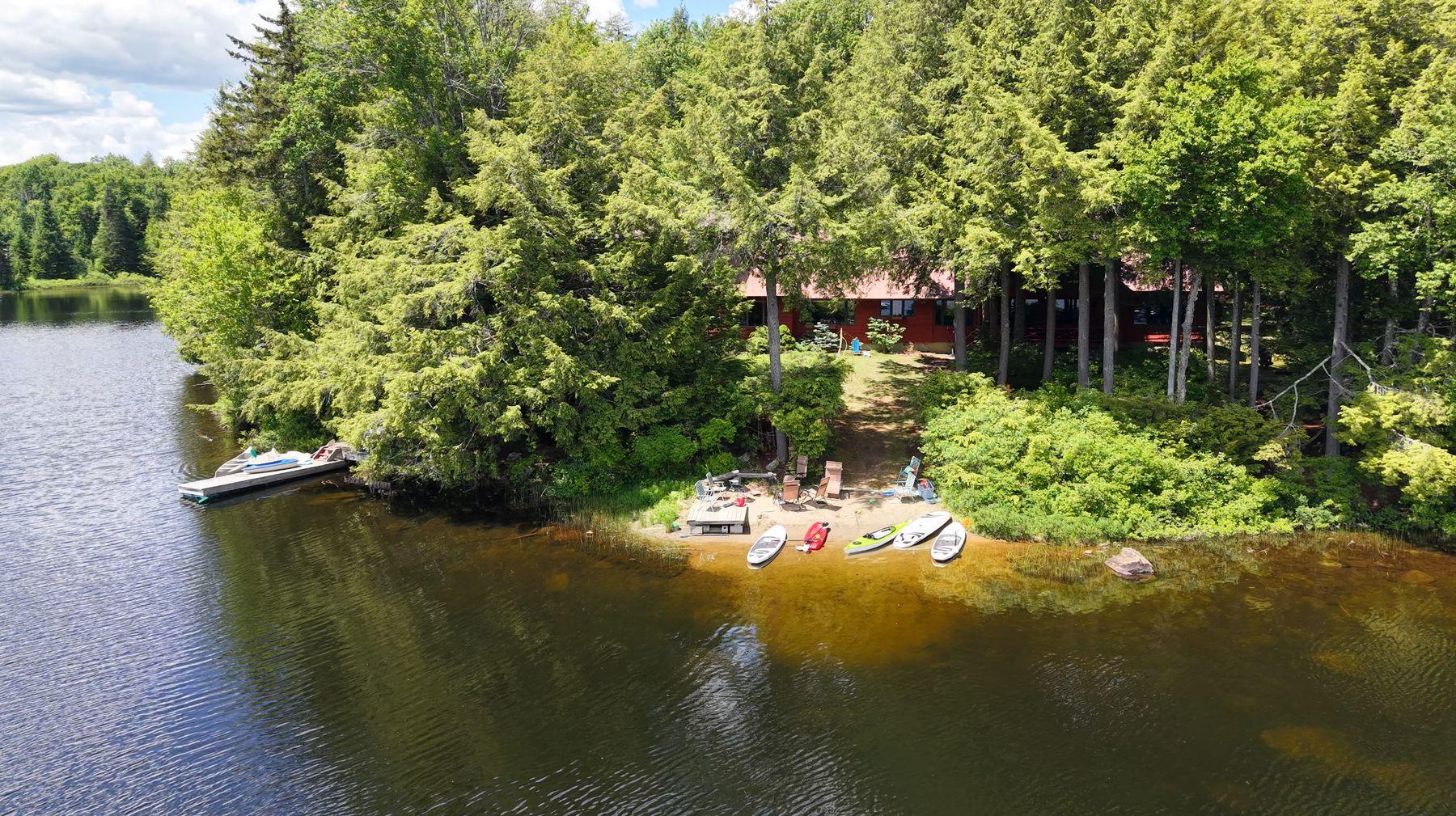 The cabin's beach and dock with paddleboards on the sand